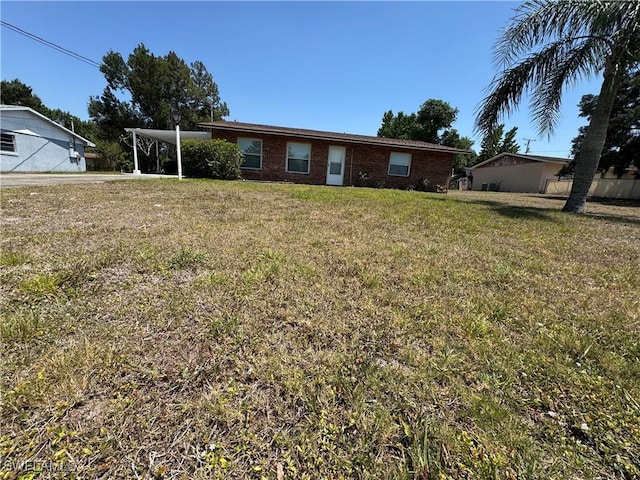 ranch-style home with a front yard, a carport, and brick siding