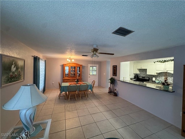 dining area with light tile patterned floors, visible vents, a ceiling fan, and a textured ceiling