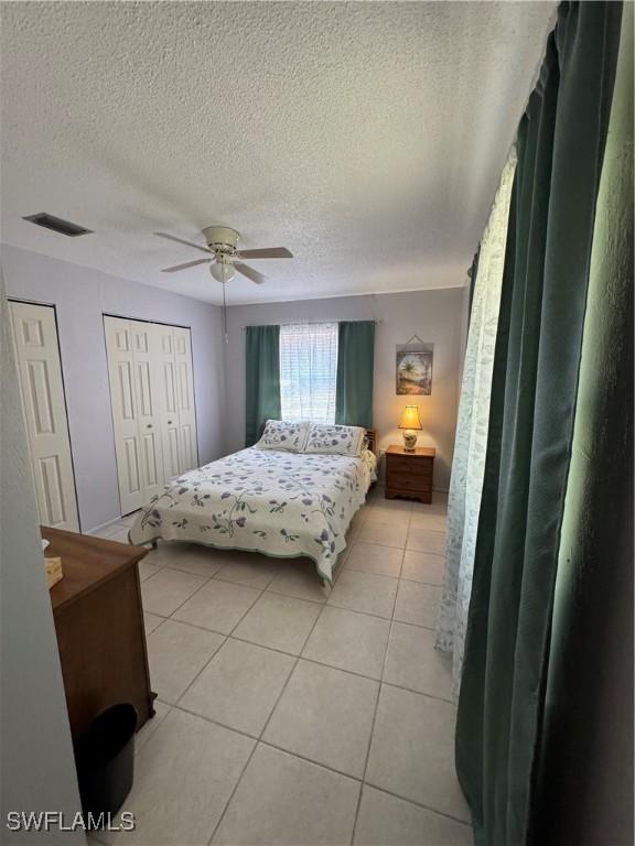 bedroom featuring visible vents, light tile patterned floors, a ceiling fan, and a textured ceiling