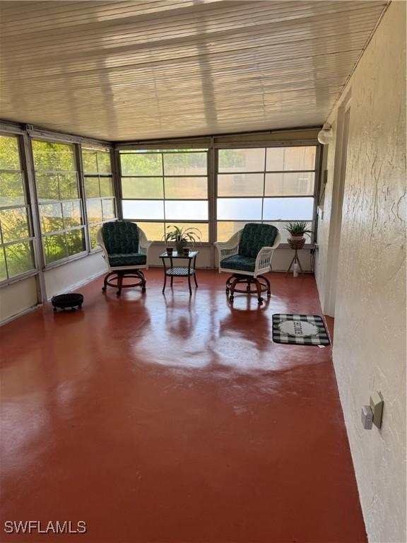 sunroom / solarium with a textured wall and finished concrete floors