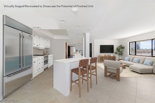 26130 Hickory Blvd Unit 1B, Bonita Springs, FL 34134 - kitchen featuring stainless steel built in fridge, a kitchen bar, white cabinets, open floor plan, and a sink