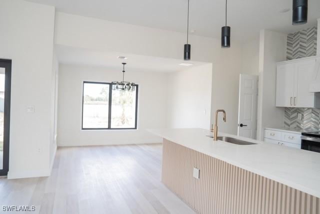 1194 Calico St, Labelle, FL 33935 - kitchen with light wood finished floors, light countertops, backsplash, a sink, and pendant lighting