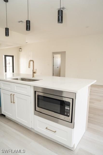 1194 Calico St, Labelle, FL 33935 - bar with stainless steel microwave, light wood-style floors, pendant lighting, and a sink