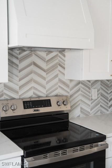 1194 Calico St, Labelle, FL 33935 - room details with electric range, white cabinets, decorative backsplash, and light countertops