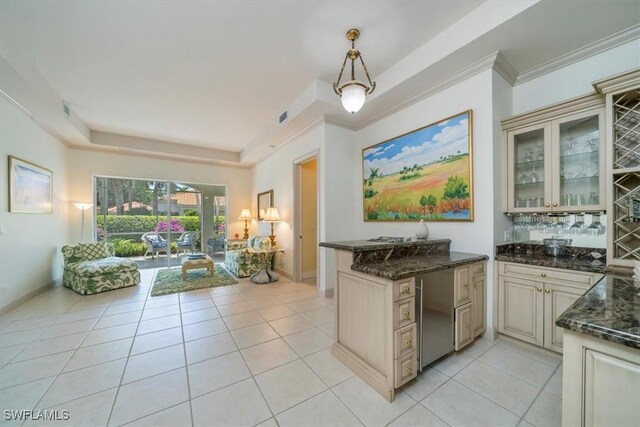 2387 Terra Verde Ln Unit 2387, Naples, FL 34105 - kitchen with crown molding, light tile patterned floors, glass insert cabinets, a raised ceiling, and cream cabinetry