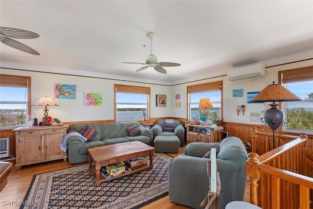 living room featuring wainscoting, plenty of natural light, a ceiling fan, and an AC wall unit