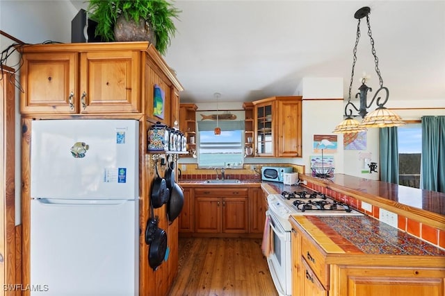 kitchen featuring a sink, a peninsula, a wealth of natural light, and white appliances