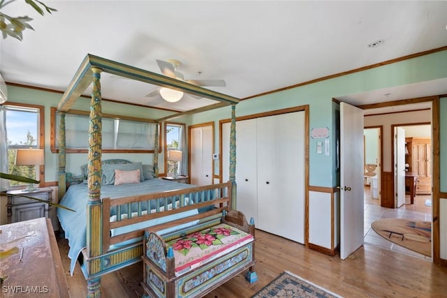 bedroom featuring ornamental molding, two closets, and wood finished floors