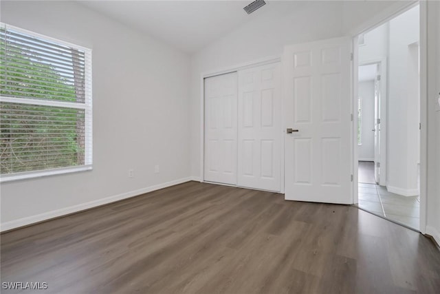 3340 33rd Ave NE, Naples, FL 34120 - unfurnished bedroom with wood finished floors, visible vents, lofted ceiling, and multiple windows
