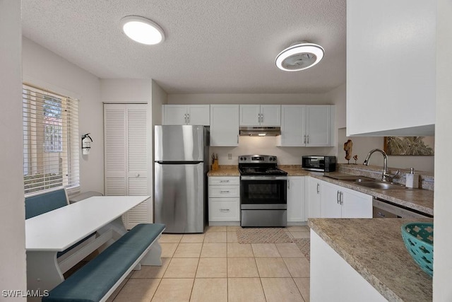 3705 Amberly Cir Unit F102, Naples, FL 34112 - kitchen with stainless steel appliances, under cabinet range hood, a sink, white cabinets, and a textured ceiling