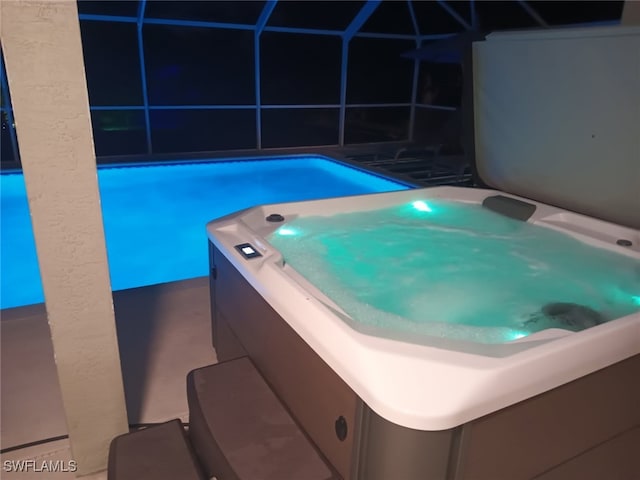 view of swimming pool featuring a pool, glass enclosure, and a hot tub