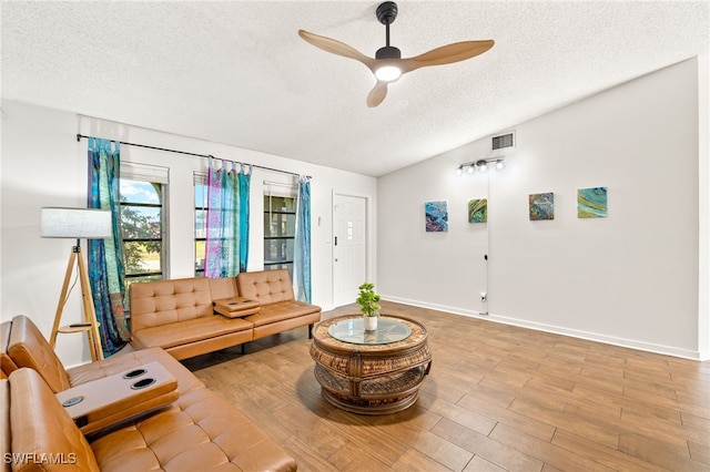 living area with a ceiling fan, visible vents, baseboards, a textured ceiling, and wood finished floors