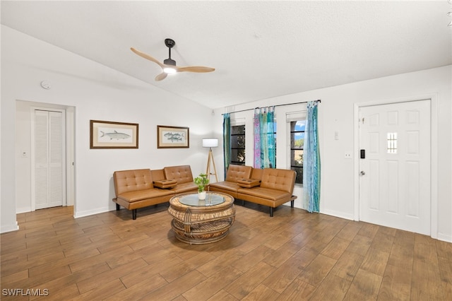 living room with baseboards, wood finished floors, a ceiling fan, and lofted ceiling