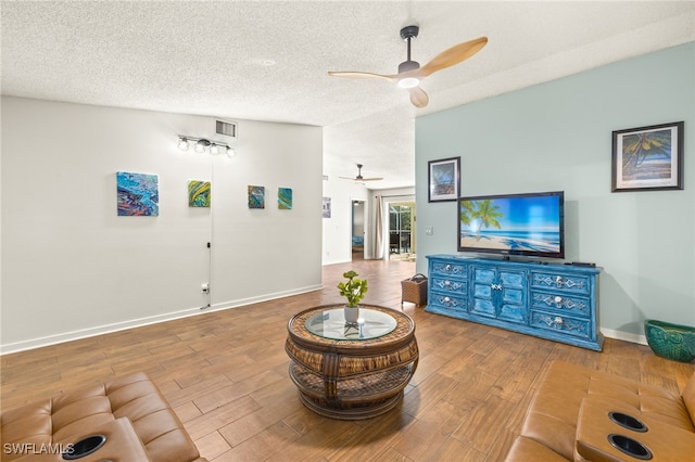 living room with a ceiling fan, visible vents, wood finished floors, and a textured ceiling