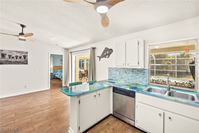 kitchen featuring a textured ceiling, stainless steel dishwasher, a sink, ceiling fan, and a peninsula