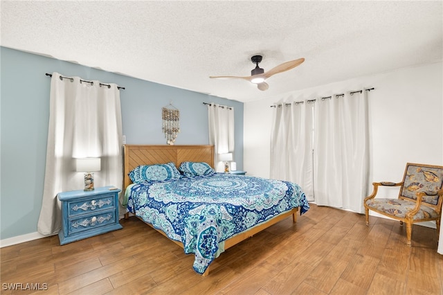 bedroom with a textured ceiling, a ceiling fan, and wood finished floors