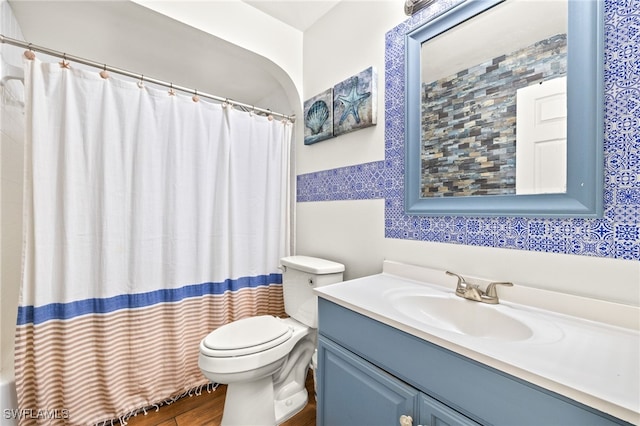 full bathroom featuring a shower with curtain, toilet, tile walls, wood finished floors, and vanity