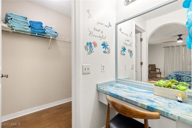 interior space with wood finished floors, a ceiling fan, and baseboards