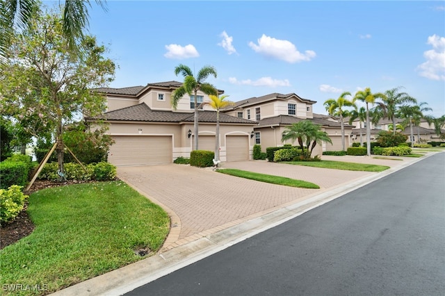 multi unit property featuring a tiled roof, stucco siding, an attached garage, and decorative driveway