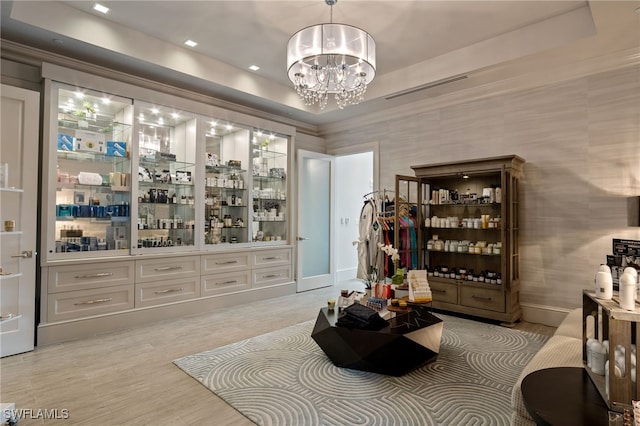 interior space with a chandelier, ornamental molding, baseboards, a tray ceiling, and pendant lighting
