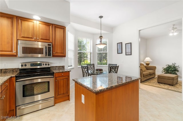 kitchen with dark stone counters, appliances with stainless steel finishes, brown cabinets, and light tile patterned flooring