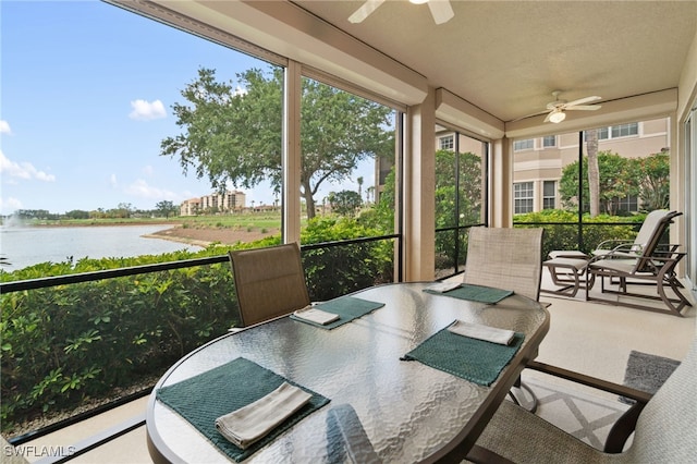 sunroom featuring a water view, a ceiling fan, and outdoor dining area