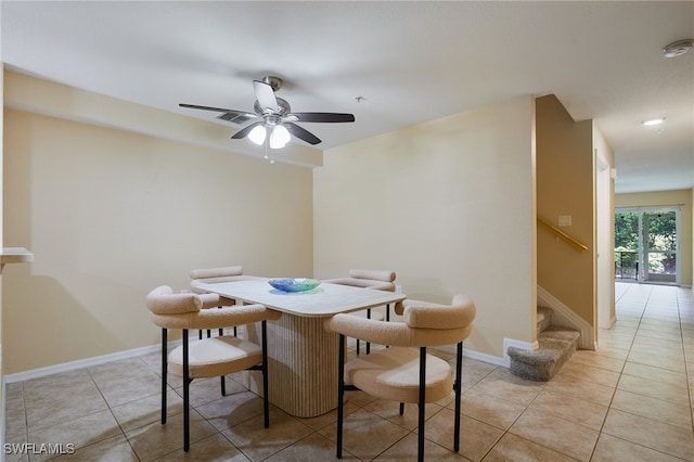 dining room with light tile patterned floors, a ceiling fan, stairs, and baseboards