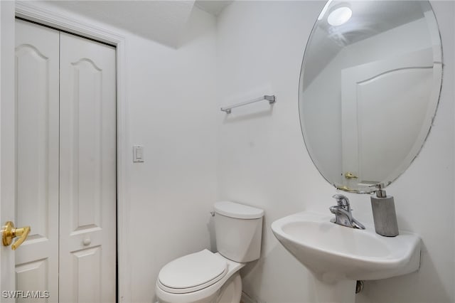 half bath featuring toilet, a sink, and a closet