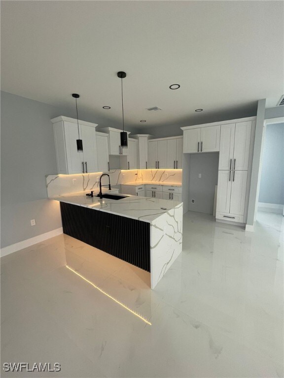 2710 10th St SW, Lehigh Acres, FL 33976 - kitchen featuring a sink, baseboards, light stone countertops, white cabinetry, and recessed lighting