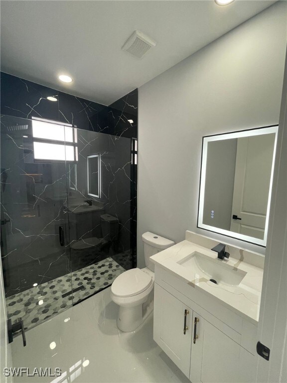 2710 10th St SW, Lehigh Acres, FL 33976 - bathroom with a marble finish shower, vanity, toilet, and recessed lighting