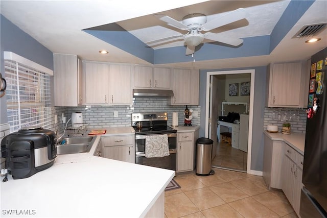 kitchen with under cabinet range hood, light countertops, a sink, range with two ovens, and visible vents