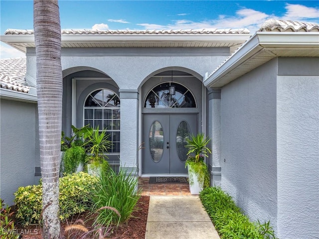property entrance featuring french doors, stucco siding, and a tiled roof