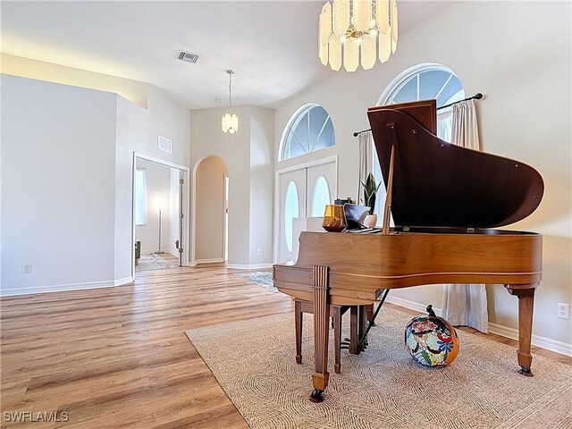 interior space with visible vents, baseboards, arched walkways, a towering ceiling, and wood finished floors
