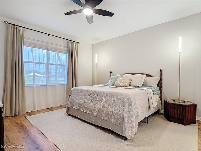 bedroom featuring light wood-type flooring, a ceiling fan, and baseboards