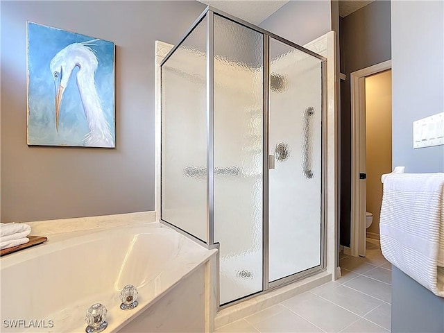 bathroom featuring a stall shower, tile patterned flooring, toilet, and a garden tub