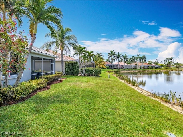view of yard with a sunroom and a water view
