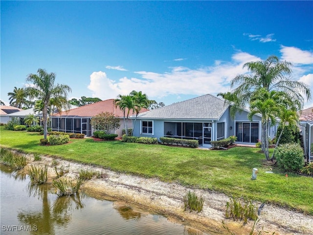 rear view of property featuring a lawn, a water view, stucco siding, and a sunroom