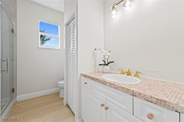 full bathroom with wood finished floors, a shower stall, baseboards, and toilet
