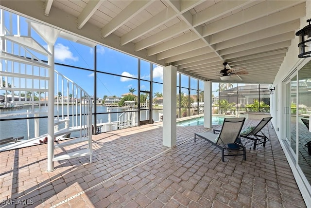 sunroom featuring ceiling fan, a water view, and beamed ceiling