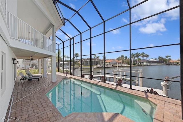 outdoor pool with boat lift, a boat dock, a patio, a water view, and a ceiling fan