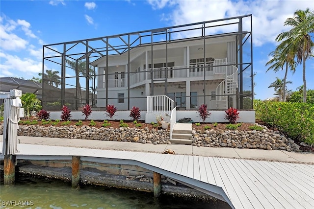rear view of property with stairs, a water view, and a lanai