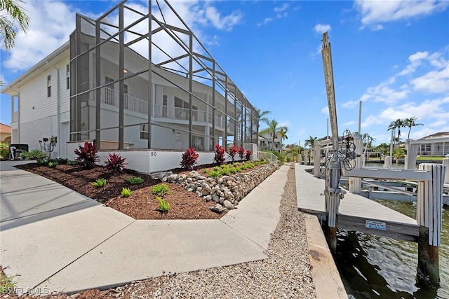 view of side of home featuring boat lift, a boat dock, and glass enclosure