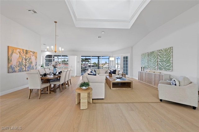 living room featuring light wood-style flooring, a chandelier, baseboards, and a tray ceiling