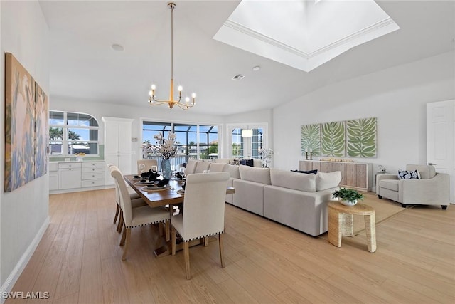 dining space with a chandelier, light wood-style flooring, baseboards, and vaulted ceiling