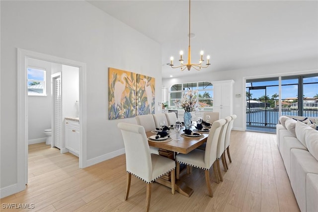 dining area featuring a chandelier, light wood-type flooring, baseboards, and a water view