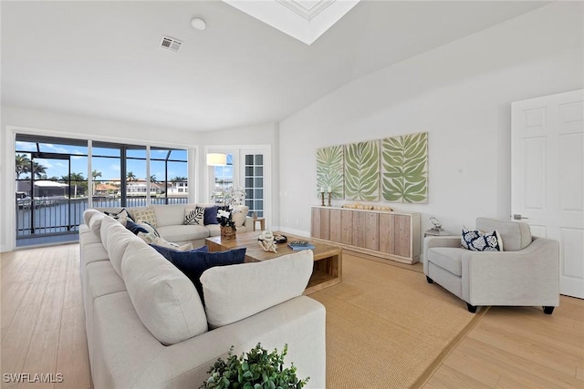 living area with light wood-type flooring, a skylight, and a water view