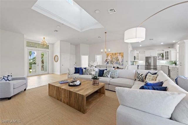 living room featuring a chandelier, recessed lighting, light wood-type flooring, and french doors
