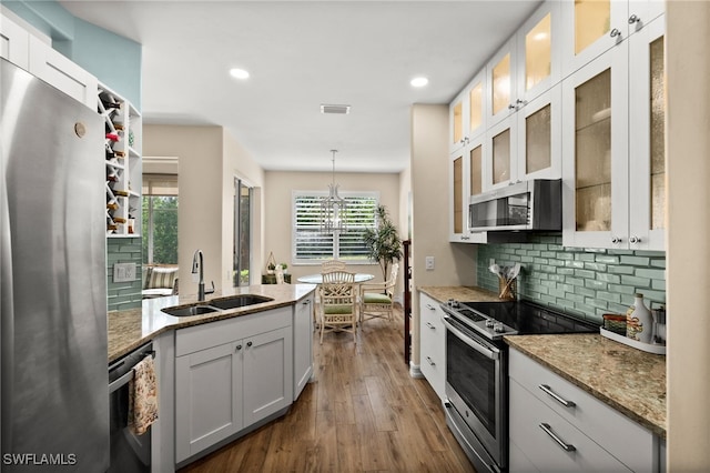 770 Tarpon Cove Dr Unit 702, Naples, FL 34110 - kitchen featuring stainless steel appliances, tasteful backsplash, dark wood finished floors, hanging light fixtures, and light stone countertops