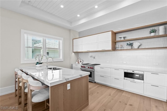 201 8th St S Unit 301, Naples, FL 34102 - kitchen featuring light stone counters, high end stove, a kitchen bar, a raised ceiling, and light wood-style floors