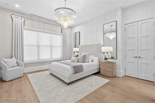 201 8th St S Unit 301, Naples, FL 34102 - bedroom with baseboards, a notable chandelier, and light wood-style flooring